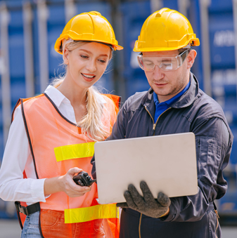 Female and male workers looking at the open laptop with cargo containers in the background